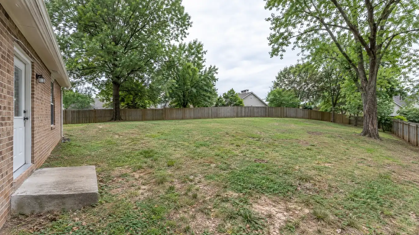 Bare patchy backyard with a wooden fence before a patio and outdoor kitchen were built