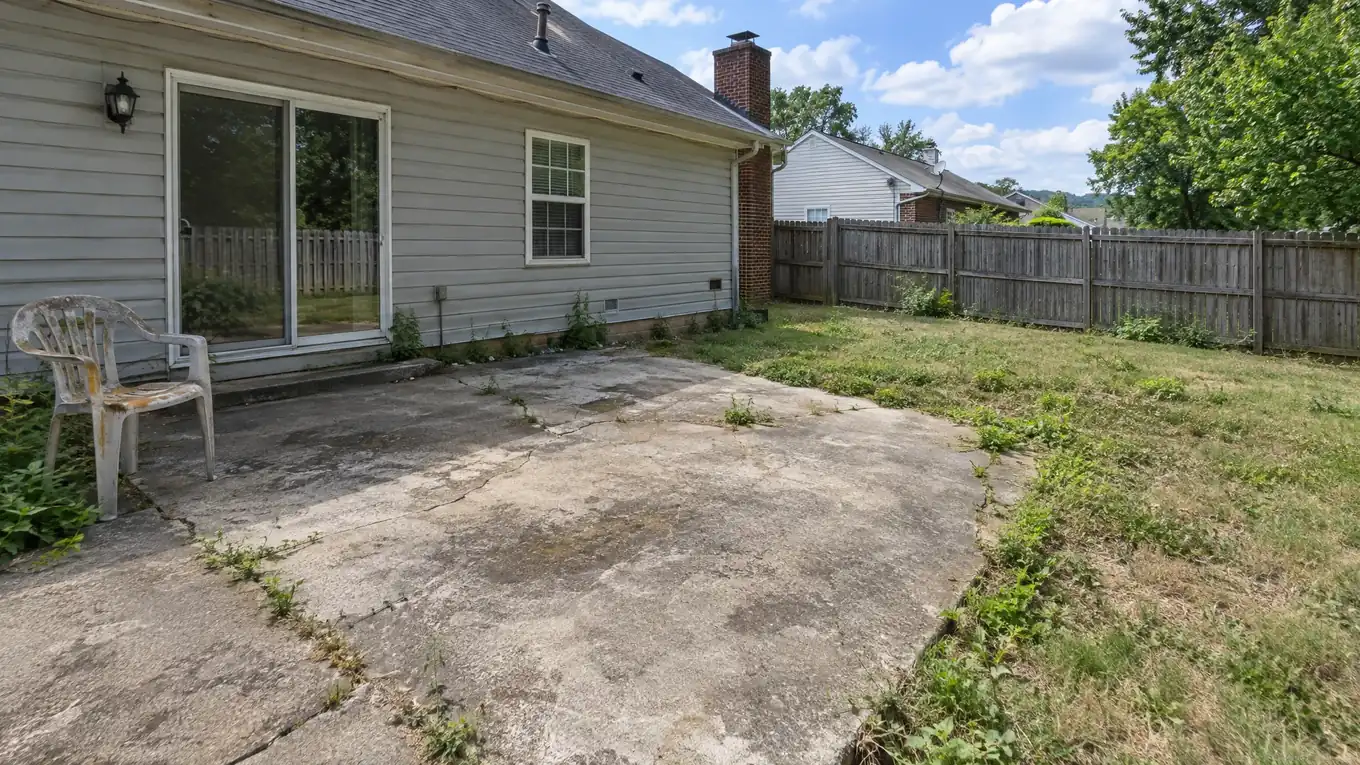 Old cracked gray concrete patio slab with weeds before it was replaced