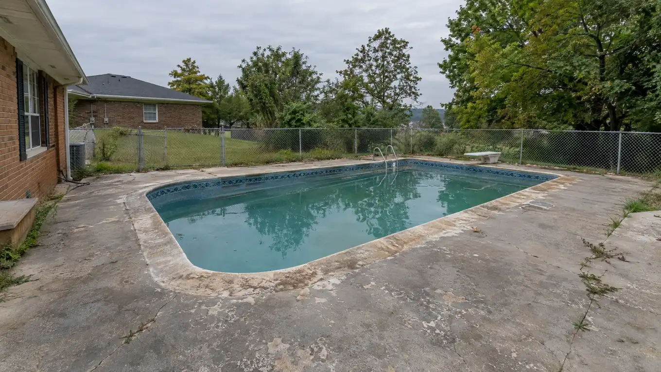 Worn pool deck with cracked gray concrete and stained coping before the refresh